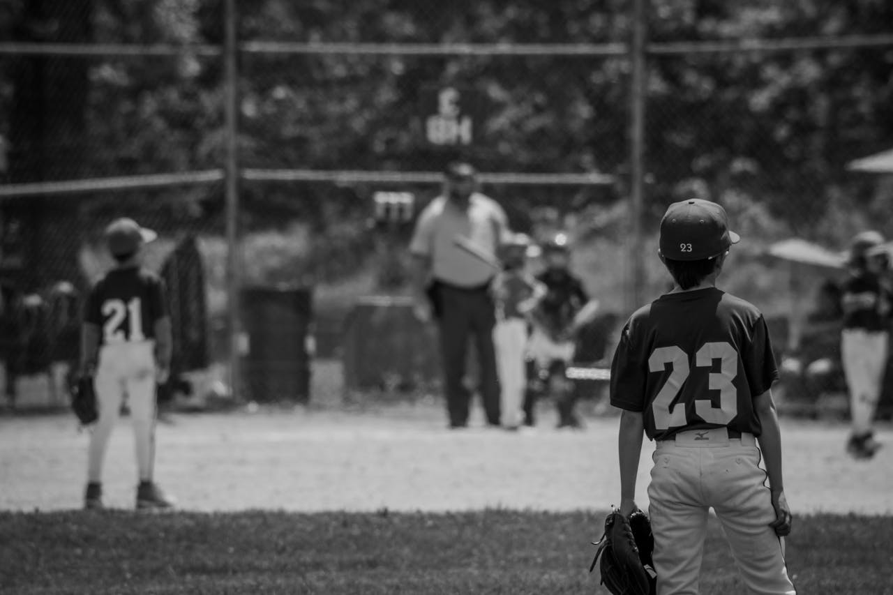 Monochrome scene of young baseball players on a field with uniforms and equipment.