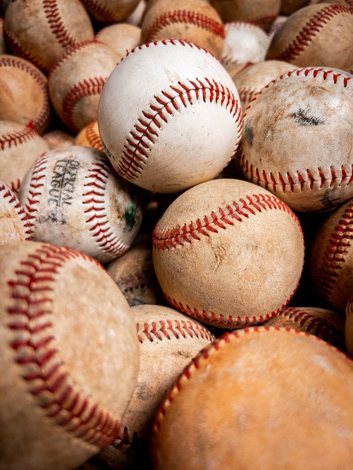 Close-up view of a pile of well-used baseballs with red stitching.